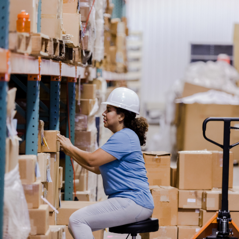 A woman sitting in the warehouse with full of boxes around